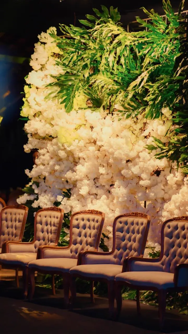 Parede de flores brancas com cadeiras capitonê