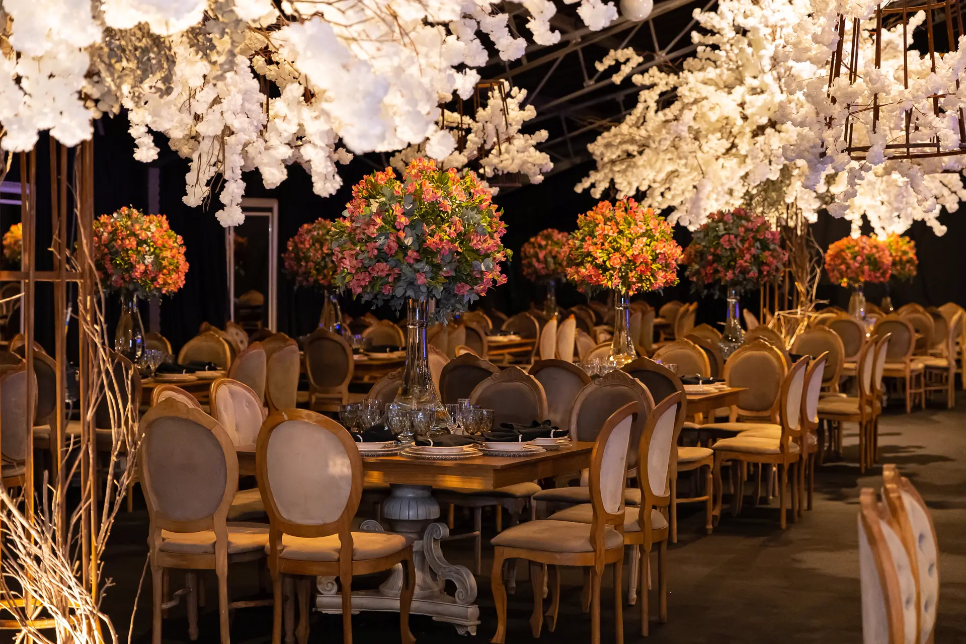 Salão decorado com mesas redondas e árvores de flores