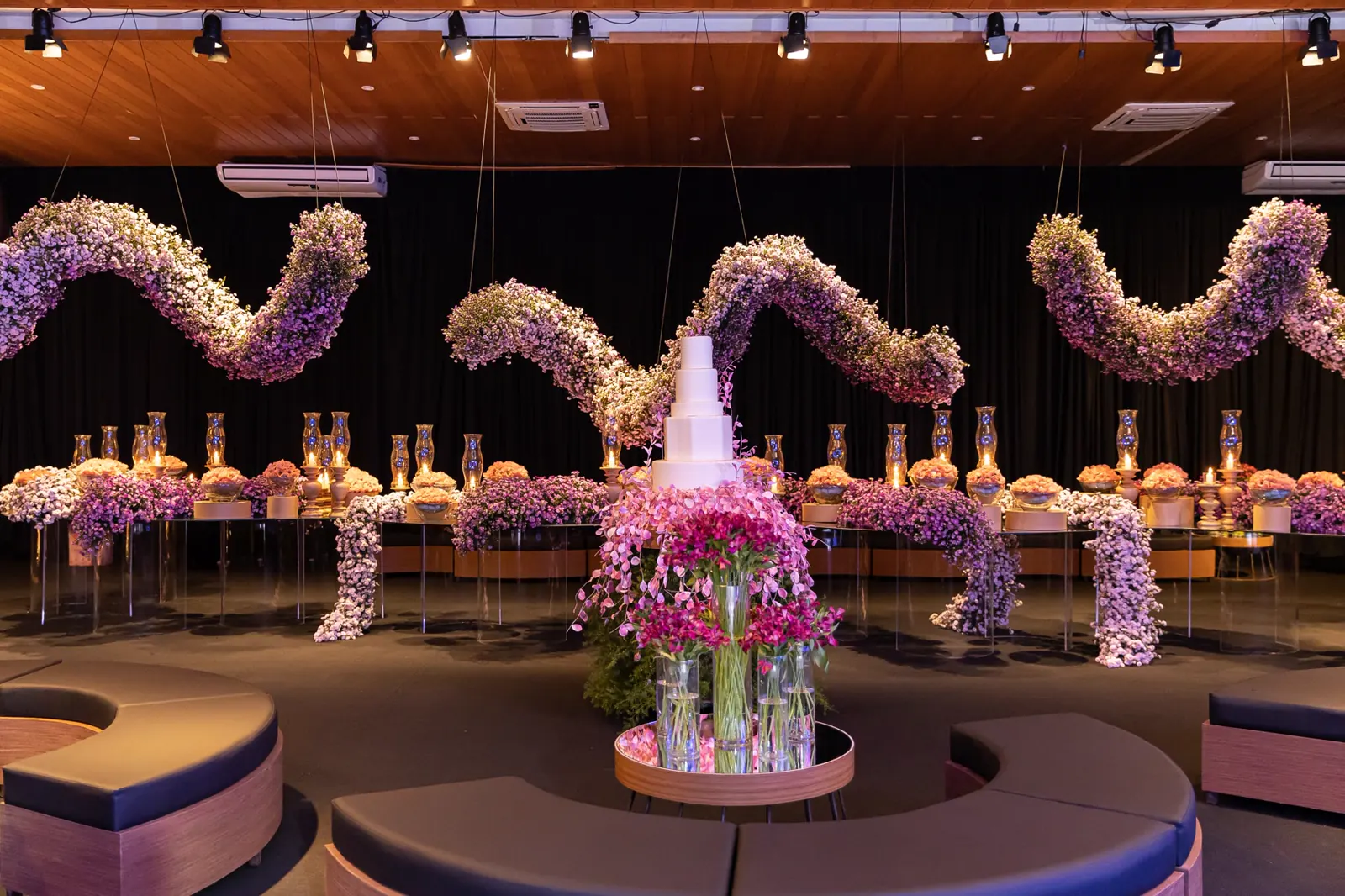 Salão decorado com arcos de flores e mesas postas